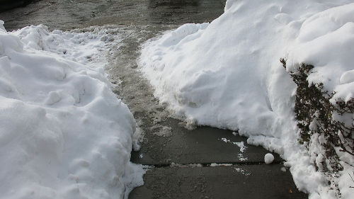 A narrow, slippery passage between two snow piles.
